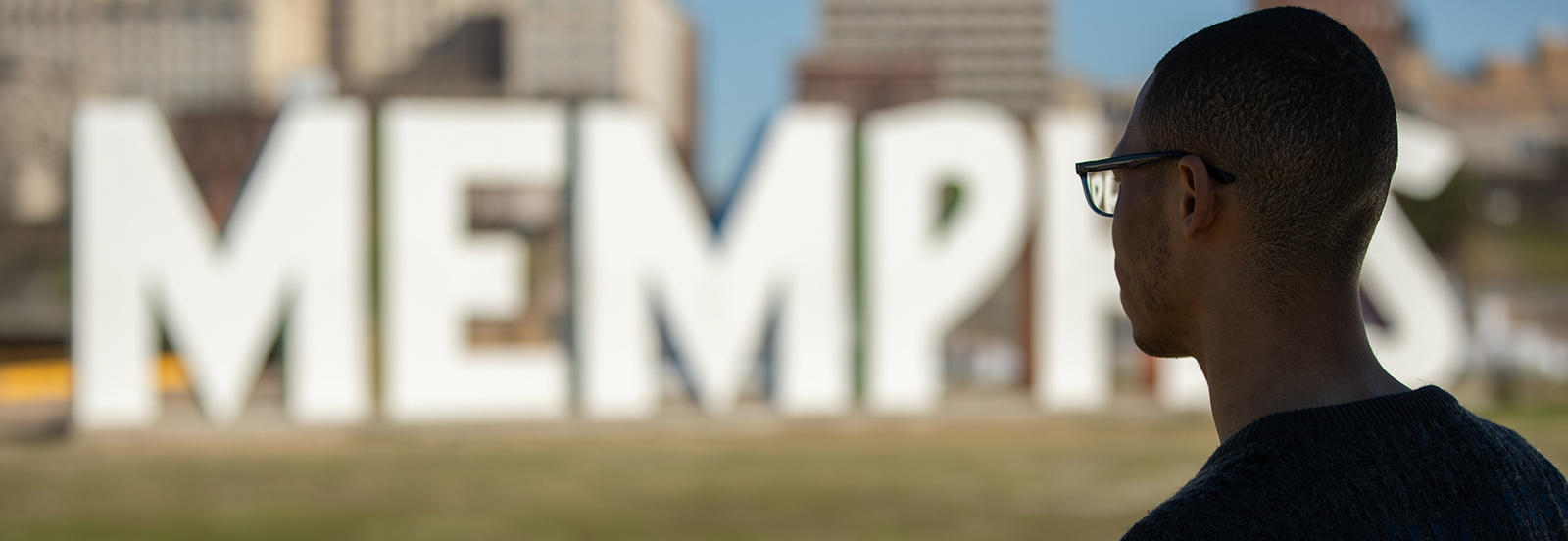 large letters spelling MEMPHIS in background with back of student in foreground