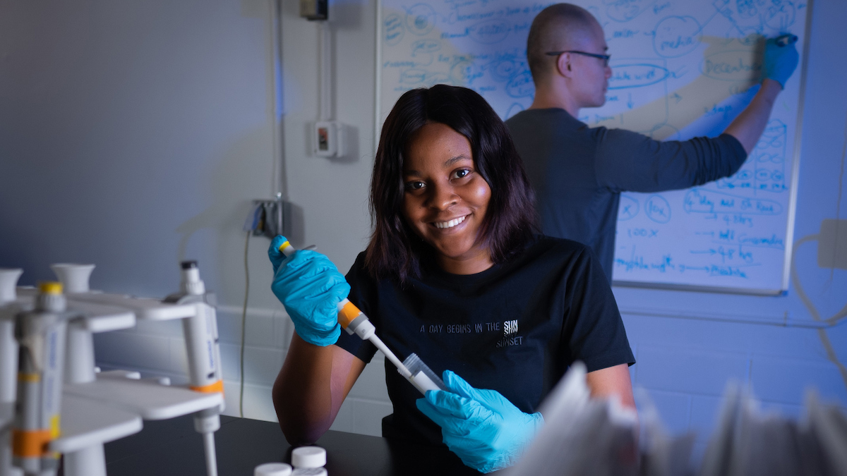 graduate student in lab coat smiling in reflection