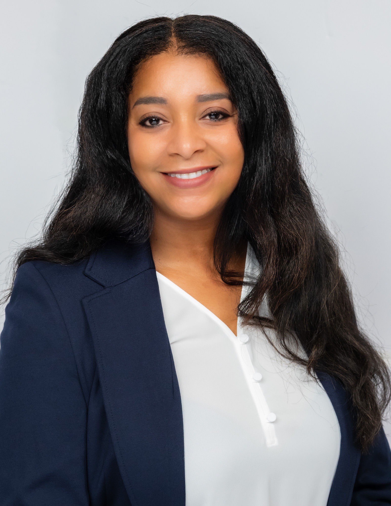 Jabionna Bolden smiles for the camera. She is wearing a white blouse and blue blazer.  