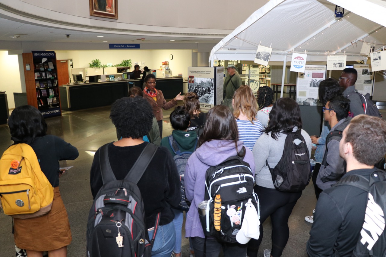 Hooks Executive Director Daphene McFerren speaks to students in front of the "Uplift the Vote" exhibit.