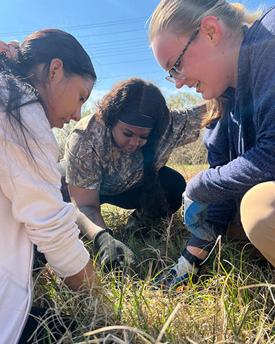 Three students studying the ground