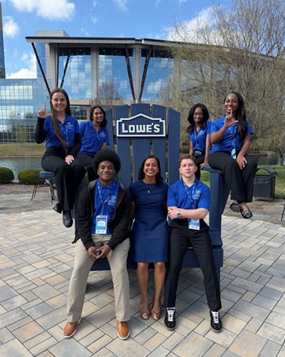 FBCE students pose for photo sitting on chair outside of Lowe's headquarters.