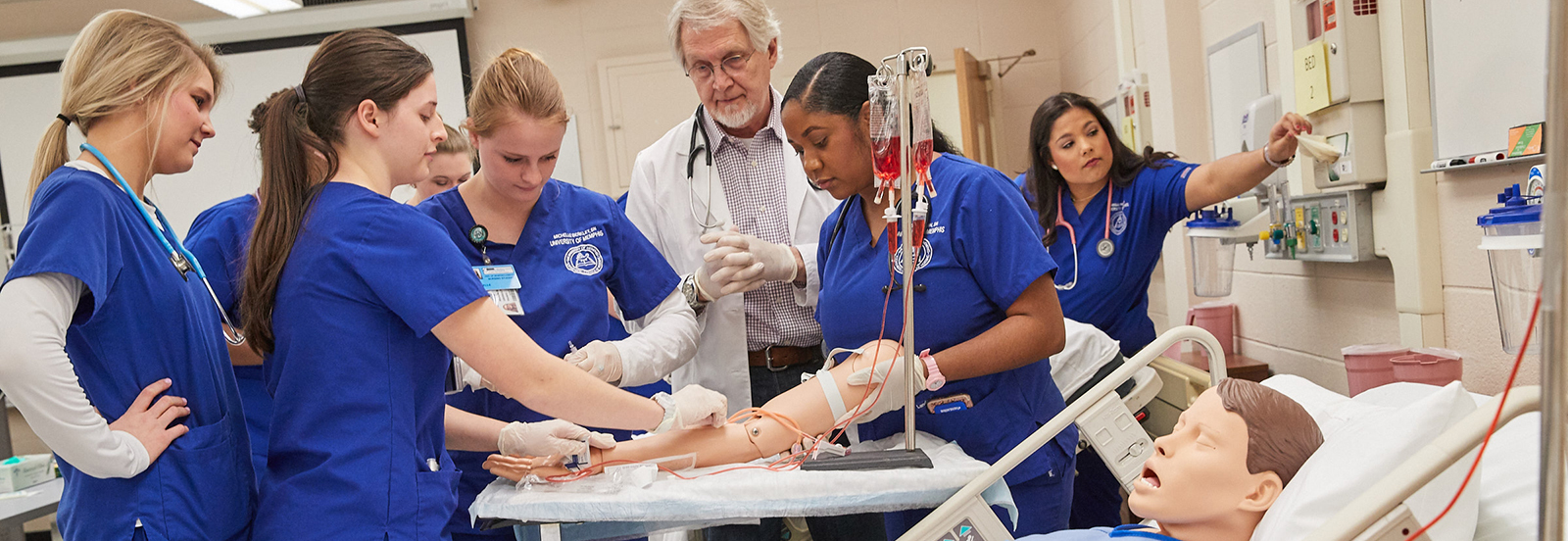 Seven Nursing Students and an Instructor go through a clinical practice procedure with a test dummy.