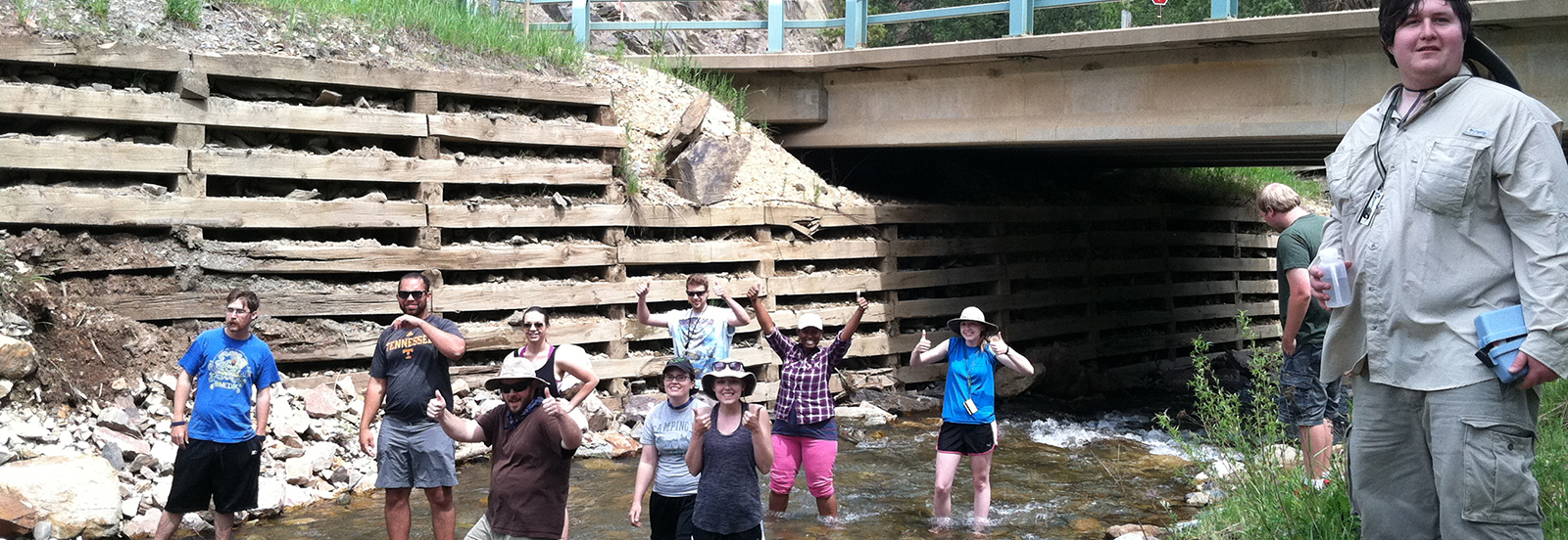ESCI 4622, Geology Field Camp, students measuring stream discharge and cooling off at Lead, South Dakota.