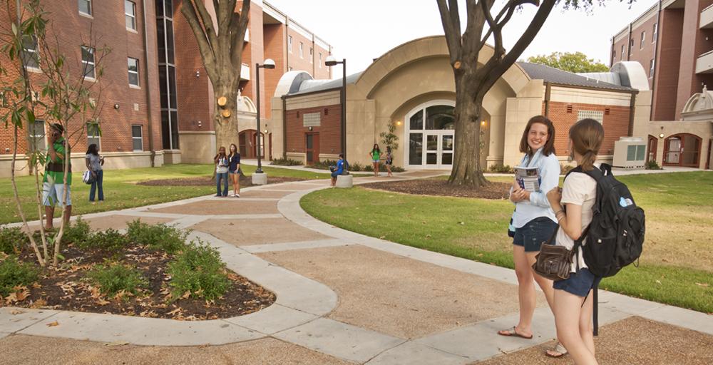 students walking on landscaped designed pathways near front entrance hub area of Living Learning Complex (LLC) area