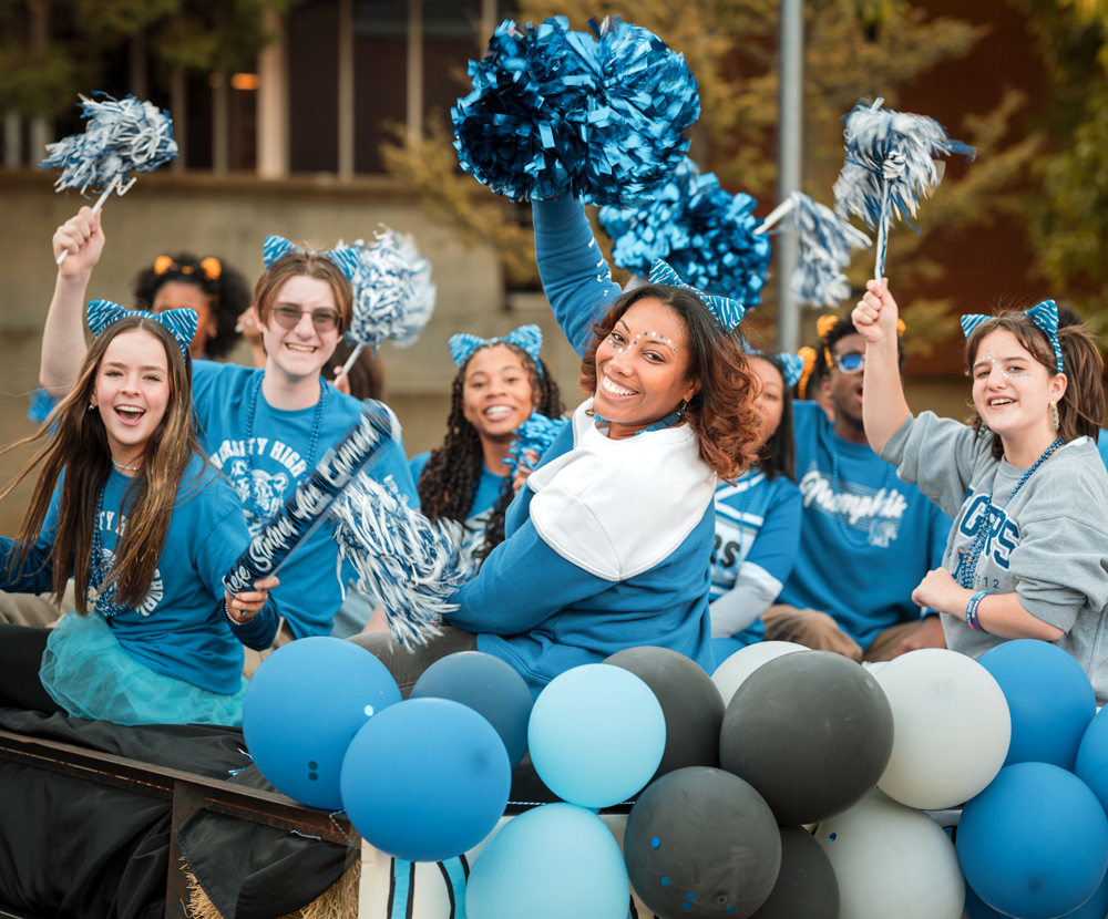 Homecoming parade participants waving pom poms