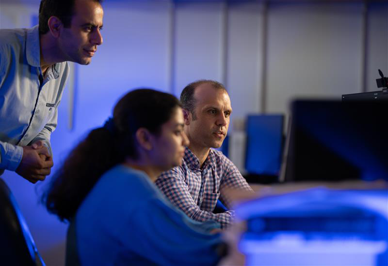 Three researchers reviewing data on a computer screen