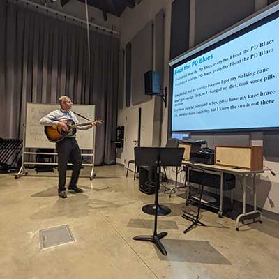 Professor Jim Pierce plays guitar and sings during a therapy session