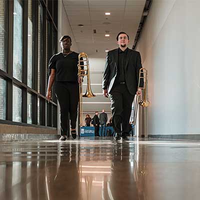 Two Scheidt School of Music students walking with their trumpets