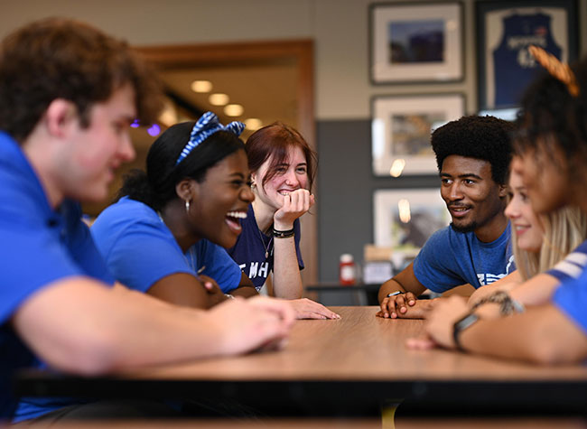 students sitting at table and laughing