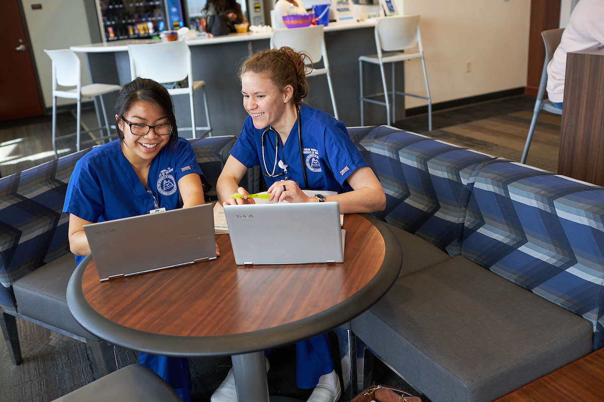 two nursing education graduate students on laptops